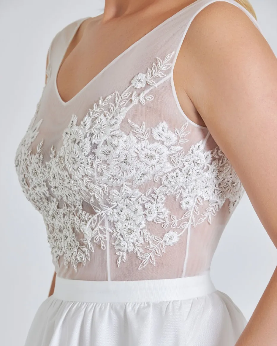 Hand-beaded floral appliqué on a sheer tulle bodice, seen close.