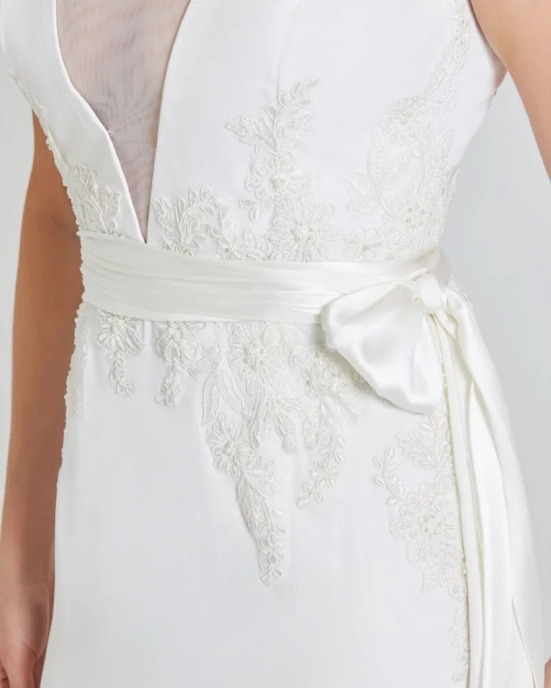 Beaded lace appliqué hand-sewn along the seam lines of a silk bodice, with a satin sash at the waist.