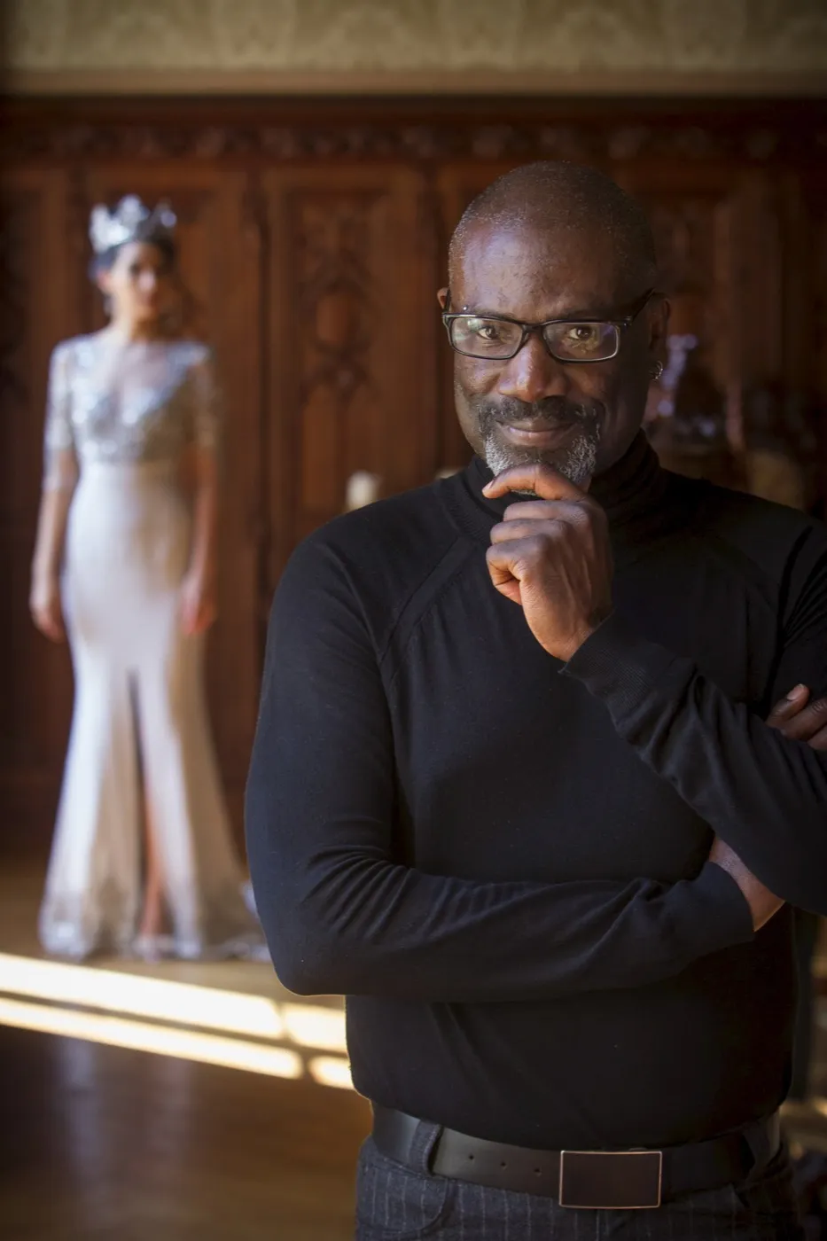 Yemi Osunkoya in the atelier, a model in a beaded gown behind him.